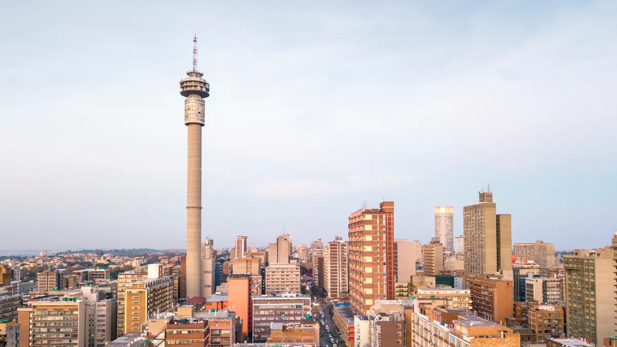 City skyline at dusk with a prominent tower and surrounding high-rise buildings.